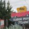 Rustic Route 62 sign for Karoo Moon Motel, featuring a red vintage car, surrounded by agave plants and trees.